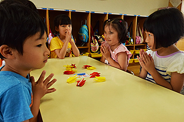 「折り鶴を前に手を合わせて祈りを込める子どもたち」の画像